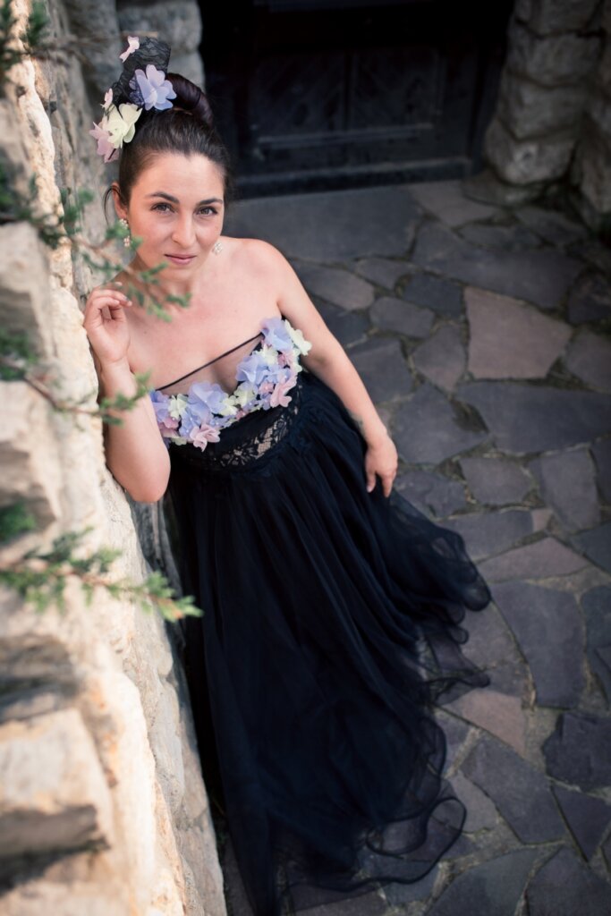 Elegant woman in a floral top and black tulle skirt posing outdoors on stone pavement